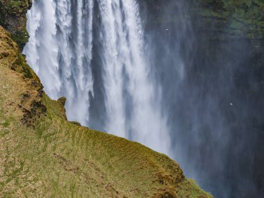 Gün batımında İzlanda 'nın etkileyici güzellikte doğası. Skogafoss şelalesi İzlanda 'nın ünlü bir doğal dönüm noktasıdır. Turistler ünlü şelale yakınlarında ata binerler..