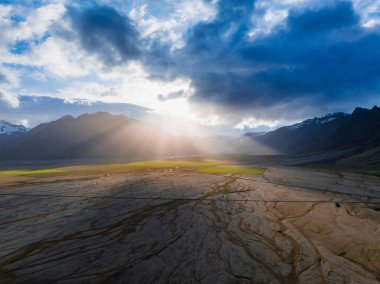 İzlanda 'nın göz kamaştırıcı görüntüsü kuru, çatlamış arazi, güneşin yansıttığı uzun gölgeler. Mavi gökyüzünün altında karla kaplı dağlar yükseliyor..