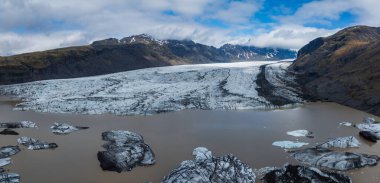 İzlanda 'da çatlamış buzullar ve görkemli dağlarla çevrili sütlü, mavi-gri bir buzul gölü. Büyük buz kütleleri durgun suda yüzer..