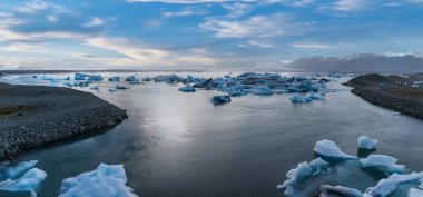 İzlanda 'daki Jokulsarlon buzulunda eriyen zümrüt turkuaz mavisi buzdağlarıyla güzel bir gün batımı..