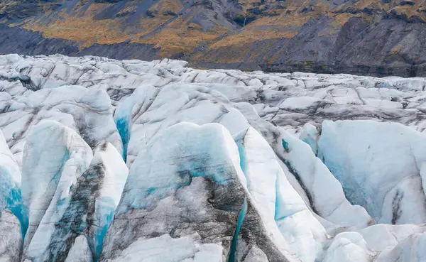 stock image Stunning aerial view of a glacier in Iceland, showcasing deep crevasses and beautiful blue ice. The light reflects off the icy surface, highlighting its natural beauty.