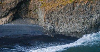 İzlanda 'da eşsiz bazalt sütunlara ve okyanus dalgalarına sahip siyah bir kumsal görüntüsü. Çarpıcı bir doğal manzara..
