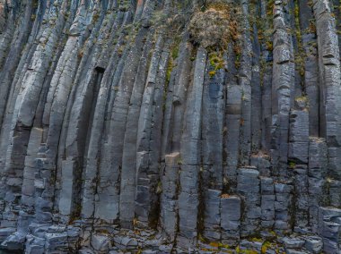 Düzenli olarak düzenlenmiş koyu gri kaya sütunlarının detaylı görüntüsü İzlanda 'nın kendine özgü jeolojik özelliklerini ve desenli yüzeylerini göstermektedir..