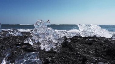 Jokulsarlon Buzulu 'nun yanındaki ünlü elmas plajına yakın volkanik siyah plajda buzdağlarının karaya oturduğu yere..