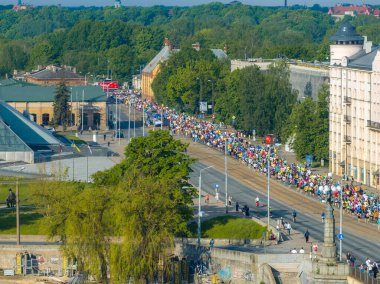 Riga, Letonya 'daki maraton koşucularının havadan çekimleri etkinliğin boyutunu gösteriyor. Geniş cadde, şehirleri aydınlatan binalar ve ağaçlarla dolu..