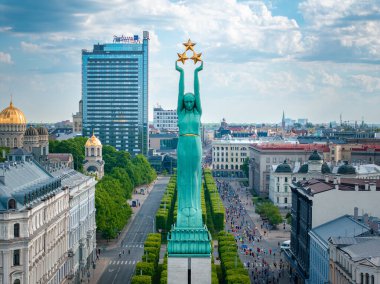 Letonya 'nın Riga kentindeki Özgürlük Anıtı' nın kuşbakışı manzarası, maraton katılımcılarıyla çevrili. Resim anıtların ihtişamını ve hareketli şehir manzarasını vurgular.