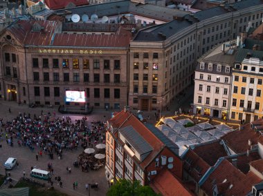 Letonya Radyo Merkezi önünde Riga, Letonya 'daki bir caddede büyük bir kalabalık toplandı. İnsanlar büyük ekranda bir yarış ya da olay izliyor..