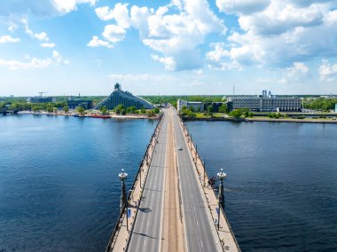 Riga, Letonya 'da tek bir araba, yayalar ve Letonya Ulusal Kütüphanesi' nin yer aldığı bir köprünün hava görüntüsü. Daugava Nehri her iki taraftan da akıyor..
