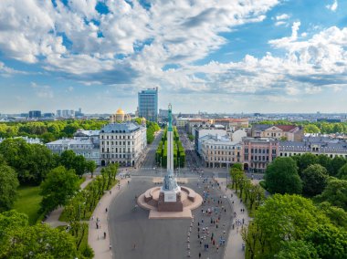 Letonya 'nın Riga kentindeki Özgürlük Anıtı' nın kuşbakışı manzarası, maraton katılımcılarıyla çevrili. Arkaplanda binalar ve ağaçların olduğu şehir manzarası görülebilir..
