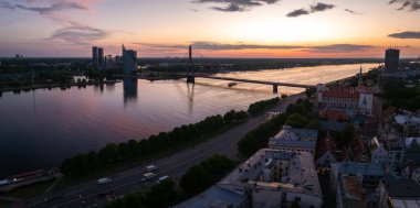 Gün batımında Riga, Letonya 'da, Daugava Nehri, Askı Köprüsü ve Riga Kalesi' nin sergilendiği muhteşem hava manzarası. Şehir batan güneşle güzelce aydınlatılır..