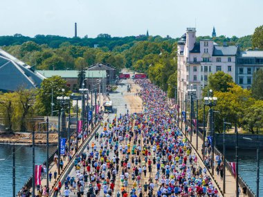 Riga, Letonya 'daki maratonun havadan çekimi. Koşucular şehrin ufuk çizgisi ile bir köprüye yayılmış, olayların boyutunu ve şehrin güzelliğini yakalıyorlar..
