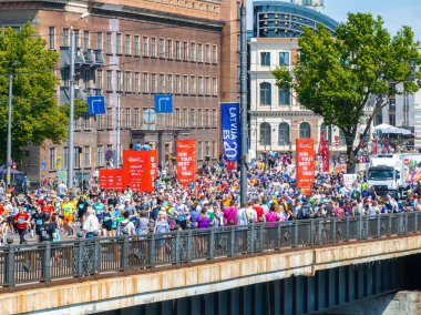 Riga, Letonya 'da Riga Rimi Maratonu sırasında büyük bir koşucu kalabalığının hava görüntüsü. Arka planda binalar ve motivasyon işaretleri görünür.