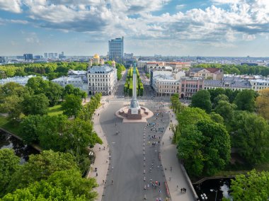Letonya 'nın Riga kentindeki Özgürlük Anıtı' nın havadan çekilmiş fotoğrafı. Etrafı maraton koşucularıyla çevrili. Görüntü, ırkın enerjisini ve şehrin güzelliğini yakalıyor..