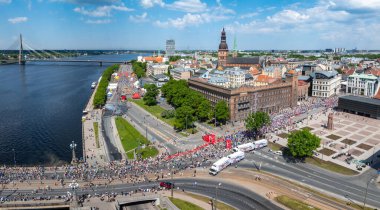 Riga, Letonya 'daki maraton koşucularını canlı bir şekilde çeken, Riga Belediye Binası ve Askı Köprüsü' nü geçen, olayların enerji ve heyecanını gözler önüne seren bir çekim..