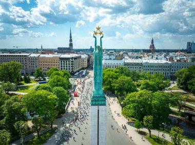 Letonya 'nın Riga kentindeki Özgürlük Anıtı' nın kuşbakışı manzarası, maraton katılımcılarıyla çevrili. Resim anıtı ve hareketli şehir manzarasını yakalar.