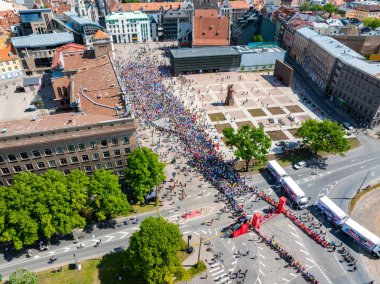 2024 Riga Rimi Maratonu 'na katılan büyük bir koşucu kitlesinin hava görüntüsü. Görüntü, caddelerde sıralanan binalar ve ağaçların yer aldığı etkinliğin boyutunu gösteriyor.