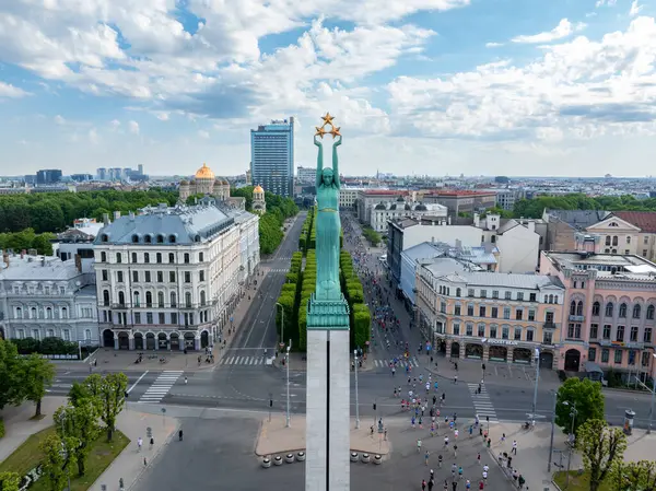 stock image Aerial shot of the Riga Rimi Marathon 2024, showcasing runners and the iconic Freedom Monument in Riga, Latvia. Captures the events energy and excitement.