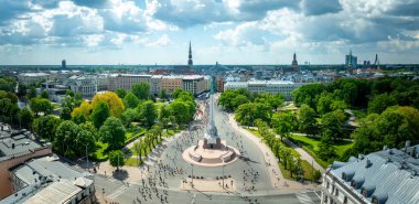 Letonya Riga 'daki Özgürlük Anıtı' nın kuşbakışı manzarası. Etrafı maraton koşucularıyla çevrili. Riga şehrinin manzarası arka planda görünür..