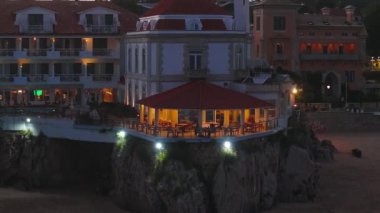 Portekiz 'in Cascais kasabası yakınlarındaki tropikal egzotik körfeze demirlemiş güzel, modern, aydınlatılmış lüks bir yatın fotokopi uzayı ile hava gecesi çekimleri.