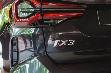 Siyah BMW iX3 lüks elektrikli SUV 'nin gösterişli ve modern tasarımı. Londra' daki bir galeride park edilmiş fren lambaları ve model rozeti var..