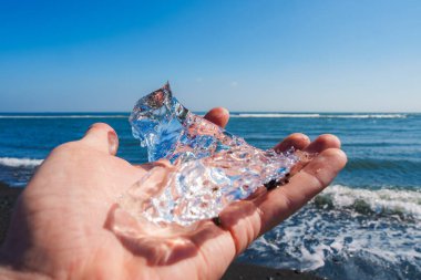 İzlanda 'da güneşli bir günde, siyah bir kumsal ve mavi bir okyanusa karşı duran temiz bir buz parçası, doğal elementlerin çarpıcı zıtlığını gözler önüne seriyor..