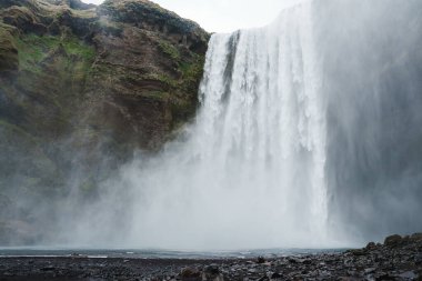 İzlanda 'daki Skogafoss şelalesi yosun kaplı kayalarla çevrili dik uçurumlardan güçlü bir akış sergiliyor ve dramatik ve resimsel bir manzara yaratıyor..