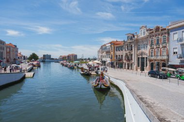 Portekiz 'in Aveiro şehrinde renkli Moliceiro tekneleri, süslemeli tarihi binalar ve açık mavi gökyüzü altında açık kafeler bulunan büyüleyici bir kanal..