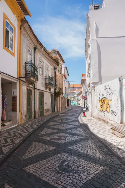 stock image A picturesque street in Aveiro, Portugal, featuring intricate cobblestone pavement, traditional buildings with wrought-iron balconies, and a clear blue sky.