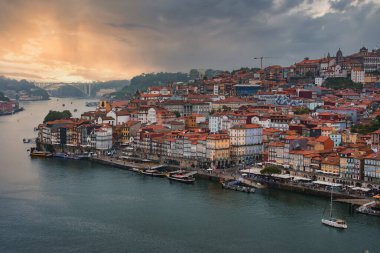 Kırmızı kiremitli çatıları olan renkli binalar Portekiz 'in Porto kentindeki Douro Nehri' ne dökülüyor. Dom Luis Köprüsü, Vila Nova de Gaia 'ya uzanan bir nehirdir..