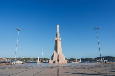 Portekiz 'in Lizbon kentindeki Keşifler Anıtı, Keşif Çağı' nı kutlamak için Tagus Nehri 'nin kıyısında duruyor. Temiz gökyüzü ve desenli asfalt ihtişamını artırıyor..