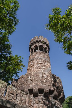 Sintra, Portekiz 'deki Quinta da Regaleira' da yemyeşil bir gökyüzü ile çevrili ve berrak mavi gökyüzüne karşı kurulmuş büyüleyici bir taş kule..