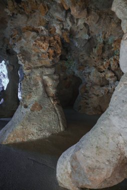 Sintra, Portekiz 'deki gizemli mağaranın içini keşfedin, dokulu taş oluşumları ve doğal ışık içeren. Topraksı tonlar ve mineral kalıntıları büyüleyici bir sahne yaratır..