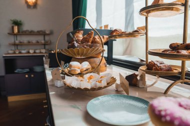 İyi aydınlatılmış, sofistike bir otel yemek alanında mermer tezgahlı iki katlı altın tepside kruvasanların ve fırınlanmış malların zarif bir gösterisi..