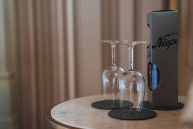 Üzerinde siyah bardak taşıyan mermer kaplı bir masa, Niepo etiketli parlak bir kutu ve şık dikey paneller olan sofistike bir otel düzeneği..