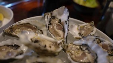 Buzda taze istiridye sunumu lüks bir otelde sofistike bir yemek deneyiminin bir parçası. Arka planda çeşitli yemekler ve servis aletleri yer alıyor.