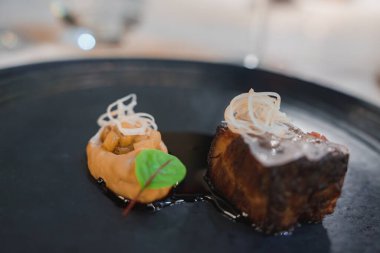 Kurutulmuş et, ince dilimlenmiş sebze ve kremalı püre içeren güzel bir kaplama gurme. Minimalist sunum aşçılık sanatını vurguluyor.