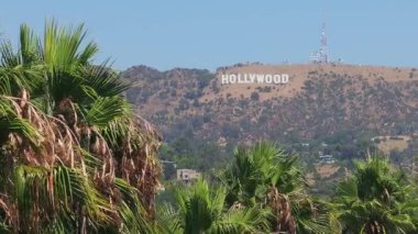 Arka planda Hollywood tabelası olan yüksek Kaliforniya palmiye ağaçlarının havadan görünüşü. Kaliforniya 'nın yaz havası. Beverly Hills yolu.