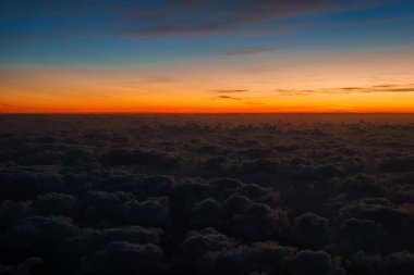 Sersemletici hava perspektifi, koyu mavi ile turuncu arası gökyüzü, dokulu bulutların üzerinde, muhtemelen Sardunya adasının üzerinde..