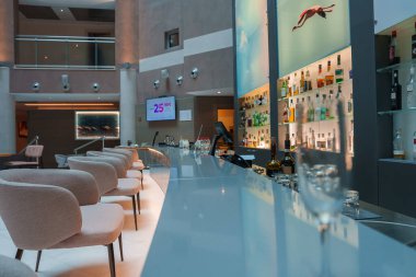 Lüks lüks bir otelin modern barında lüks koltuklar, aydınlatılmış şişe vitrinleri ve sofistike bir ortam yaratan eşsiz dalış sanat eserleri var..