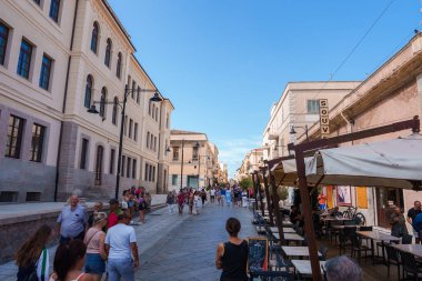 Sardinya, İtalya 'da kalabalık bir cadde. Klasik Avrupa binaları, kaldırım taşları yolları ve açık hava kafeleri var. Turistler canlı ve güneşli atmosferin tadını çıkarırlar..