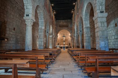 Sardinya 'daki tarihi bir Roma kilisesinin içini keşfedin. Taş duvarlar, ahşap sıralar ve haçla süslenmiş sunağa giden merkezi bir koridor..