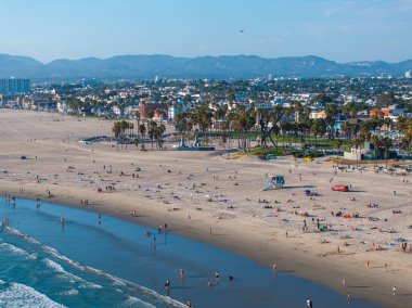 Los Angeles, Kaliforniya 'daki Venice Beach' in havadan görünüşü, kumlu kıyılar, palmiye ağaçları ve arka planda Santa Monica Dağları olan şehir manzarası..