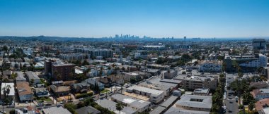Los Angeles 'ın gökyüzü perspektifi, şehir merkezi, yoğun şehir manzarası, açık mavi gökyüzü, ve arka planda uzak tepeler..