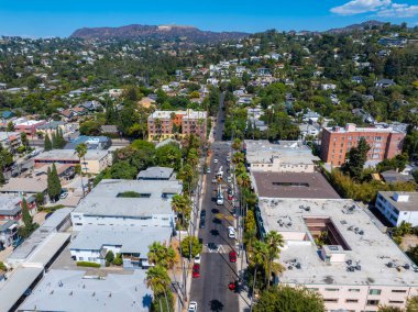 Hollywood, Los Angeles 'ta alçak katlı binalar, yemyeşil alanlar ve Hollywood Tepeleri manzaralı palmiye kaplı caddeler..