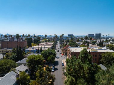 Avuç içi çizgili caddeleri, alçak binaları ve açık mavi gökyüzünün altında uzak bir ufuk çizgisi olan Los Angeles yerleşim bölgesinin havadan görüntüsü..