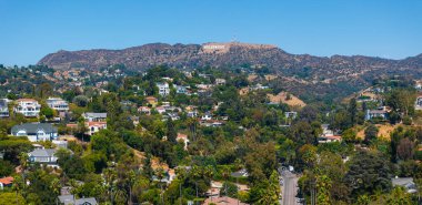 The image captures a panoramic view of Los Angeles Hollywood district, featuring the Hollywood Sign on the hills and a lush residential area in the foreground. clipart