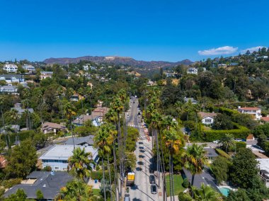 Hollywood bölgesinin havadan görünüşü, Hollywood tabelası, yemyeşil, palmiye çizgili sokaklar ve açık mavi gökyüzü..