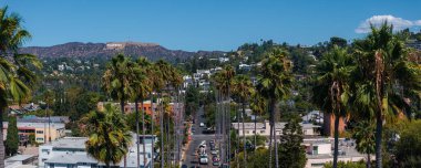 Hollywood tabelasının, palmiyeli sokakların ve konut ve ticari binaların karışımının yer aldığı Los Angeles Hollywood bölgesinin hava manzarası..