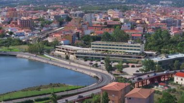 Olbia, Sardinya 'da hareketli bir meydanda bir atlıkarınca, terasotta çatısı olan binalar, açık kafeler, dükkanlar ve palmiye ağaçları yer alıyor ve canlı bir atmosferi yakalıyor..