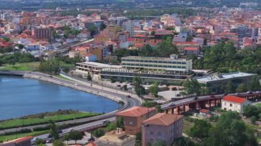 Olbia, Sardinya 'da hareketli bir meydanda bir atlıkarınca, terasotta çatısı olan binalar, açık kafeler, dükkanlar ve palmiye ağaçları yer alıyor ve canlı bir atmosferi yakalıyor..